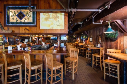 Cozy restaurant interior with wooden decor, bar seating, and a vintage photo on the wall.