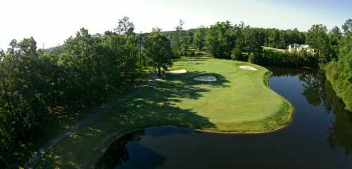 Aerial view of a golf course with green fairways, sand traps, and a pond surrounded by trees.