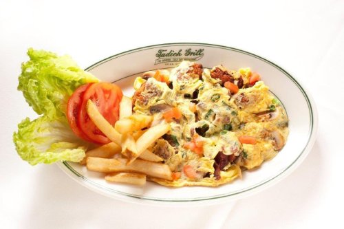 A plate of omelette with vegetables, served with lettuce, tomato, and French fries on the side.