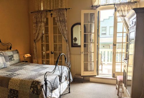Cozy bedroom with a quilted bed, elegant curtains, and a door leading to a small balcony.