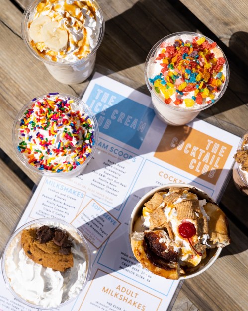 A variety of colorful milkshakes and desserts topped with whipped cream, sprinkles, and candy, alongside a menu.
