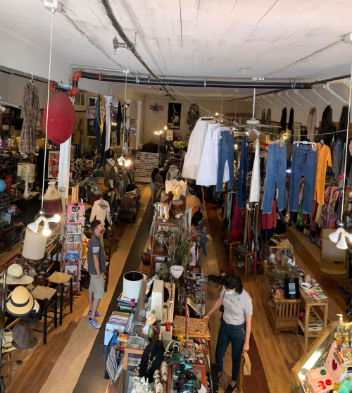 A vibrant thrift store filled with vintage items, clothing racks, and shoppers exploring the eclectic selection.