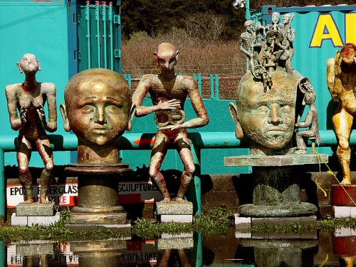 A collection of abstract sculptures featuring human-like figures and heads, set against a colorful background.
