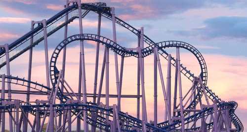 A roller coaster track with a heart-shaped loop against a colorful sunset sky.