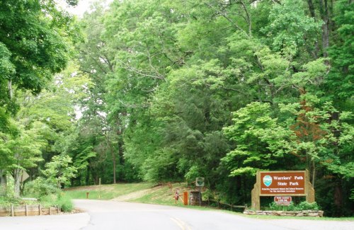 Entrance to Warriors' Path State Park, surrounded by lush green trees and a welcoming sign.