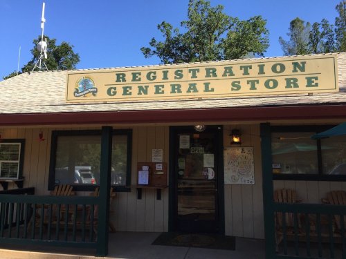 A general store with a sign reading "Registration General Store," featuring a porch and outdoor seating.