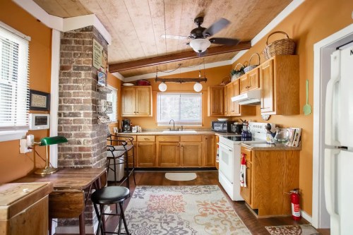 Cozy kitchen with wooden cabinets, a brick accent wall, and a dining area featuring a table and chairs.