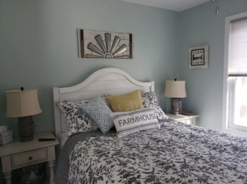 Cozy bedroom with a light blue wall, a white bed with patterned bedding, and decorative lamps on nightstands.
