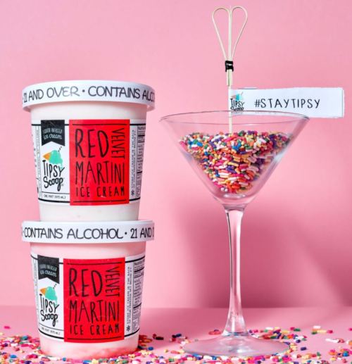 Two tubs of Tipsy Scoop Red Martini ice cream beside a martini glass filled with sprinkles on a pink background.