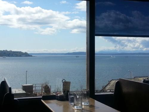 A scenic view of a calm bay with boats, mountains in the distance, and a bright blue sky from a restaurant window.