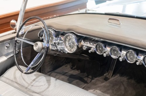 Vintage car interior featuring a sleek dashboard with chrome gauges and a classic steering wheel.