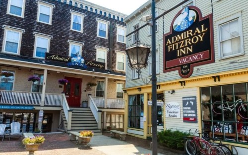 A charming inn with a sign reading "Admiral Fitzroy Inn" and a welcoming entrance, surrounded by quaint buildings.