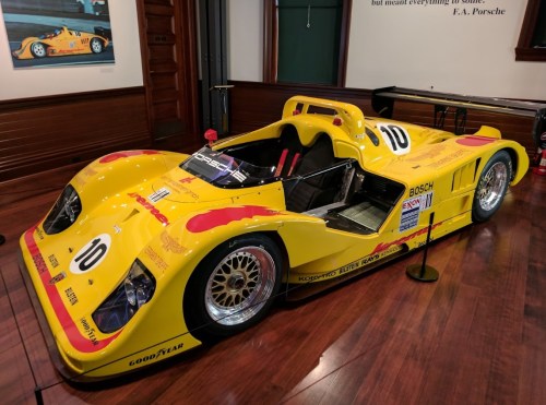 A bright yellow race car with the number 10, displayed indoors on polished wood flooring.