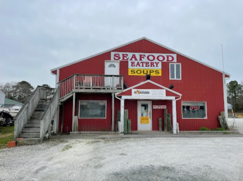 Red seafood eatery with a sign for soups, featuring stairs and a welcoming entrance. Cloudy sky in the background.