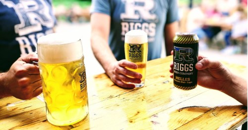 People raising Riggs Beer Company glasses and Helles lager can outside an Illinois brewery.