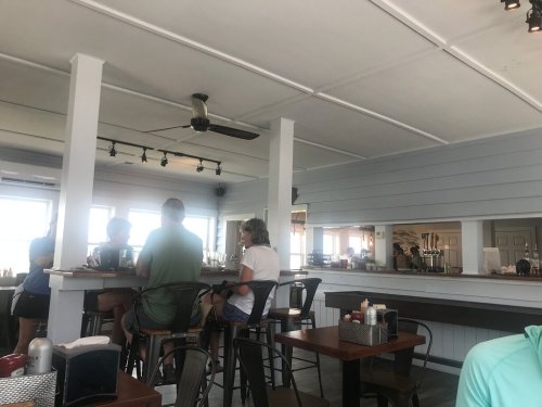 Interior of a casual restaurant with patrons seated at a bar and tables, featuring a light, airy atmosphere.