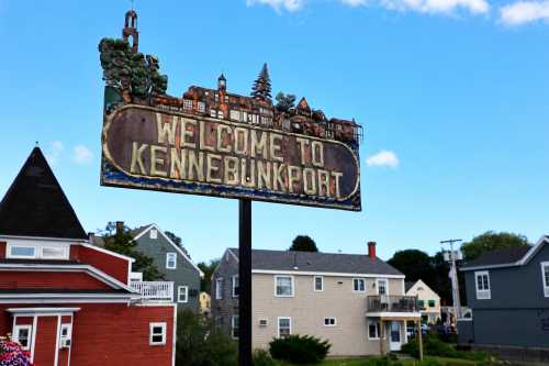 A weathered sign reading "Welcome to Kennebunkport" with a scenic illustration and colorful houses in the background.