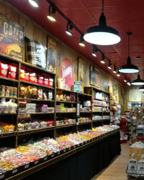 A colorful candy store with shelves filled with various sweets and treats under warm lighting.
