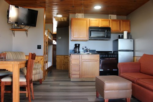 Cozy cabin interior featuring a kitchen, dining area, and living space with a sofa and TV.