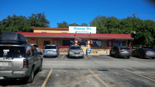 A restaurant named "Granny D's Home Cooking" with a red roof and several parked cars in front. Clear blue sky above.