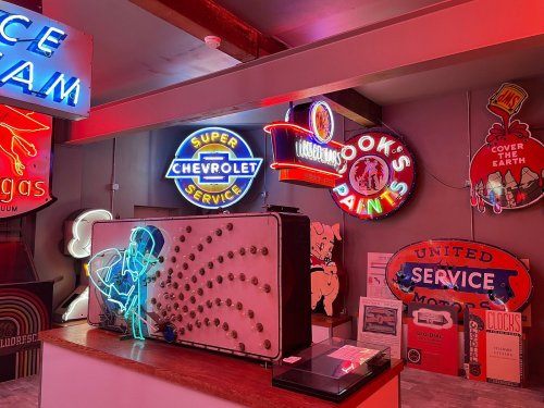 A vibrant display of vintage neon signs and memorabilia in a retro-themed room.