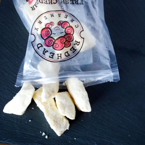 A clear bag of white snacks with a few pieces scattered on a dark surface.