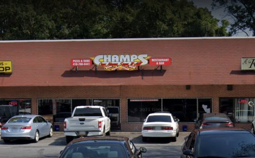Exterior of Champs Restaurant & Bar, featuring a red sign, parked cars, and a storefront in a shopping plaza.