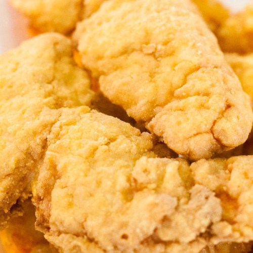 Close-up of crispy, golden-brown fried chicken tenders stacked together.