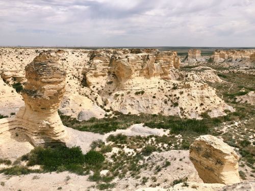 A rocky landscape with unique formations and sparse vegetation under a cloudy sky.