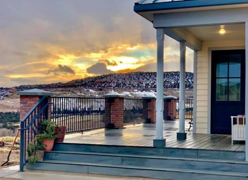 A scenic view from a porch at sunset, with mountains and a cloudy sky in the background.