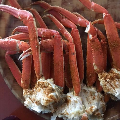A platter of cooked crab legs seasoned with spices, showcasing their vibrant orange color and tender meat.