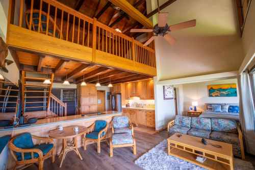 Cozy interior of a wooden cabin with a loft, featuring a living area, kitchen, and dining space.