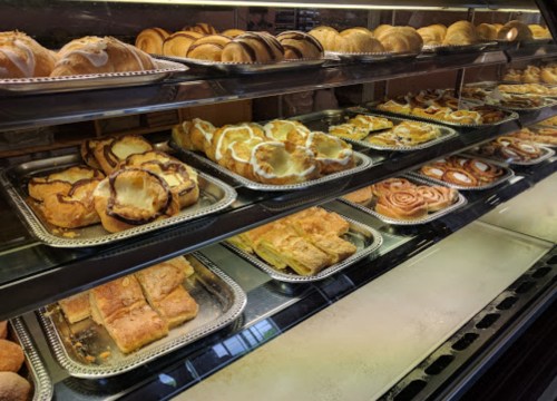 A display case filled with various baked goods, including pastries, rolls, and cinnamon buns.