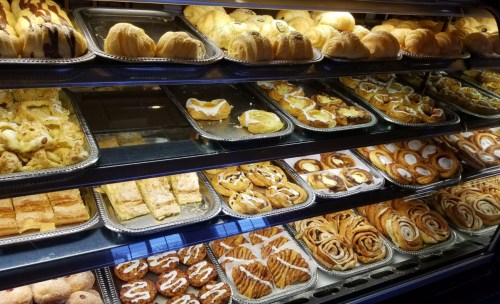 A display case filled with various baked goods, including croissants, danishes, and cinnamon rolls.