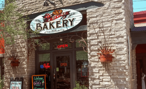 A charming bakery storefront with a sign reading "It's a Divine Bakery," featuring an open sign and welcoming decor.