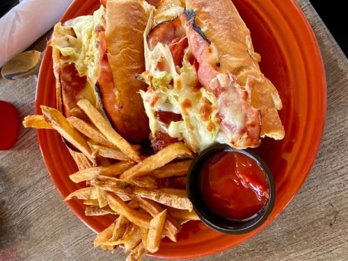 A plate with two toasted sandwiches filled with lettuce and ham, accompanied by a side of fries and a small bowl of ketchup.