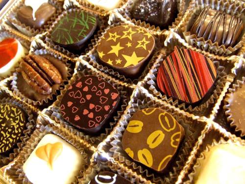 A variety of beautifully decorated chocolates arranged in a box, featuring different shapes and designs.
