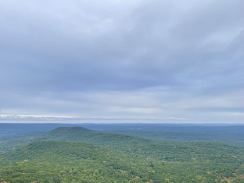 A panoramic view of rolling green hills under a cloudy sky.