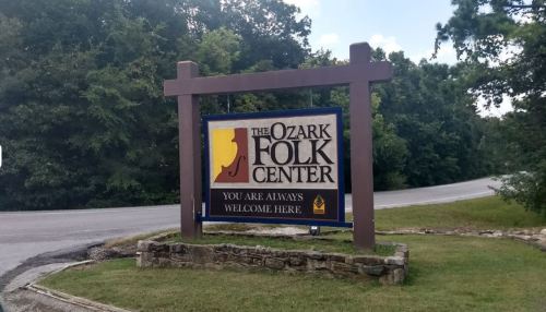 Sign for the Ozark Folk Center, stating "You are always welcome here," surrounded by trees and grass.