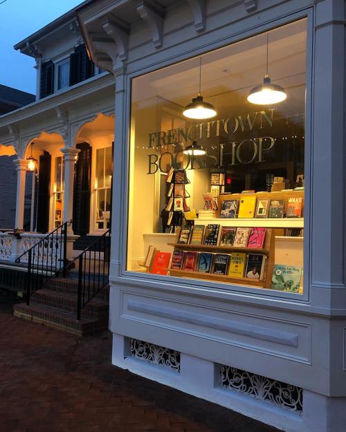A cozy bookstore window displaying colorful book covers, with warm lighting and a welcoming entrance.