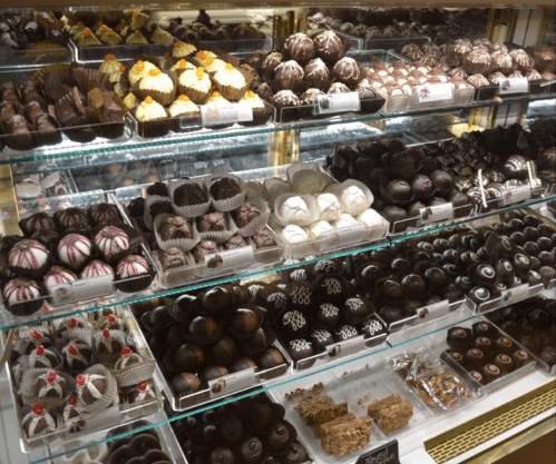A display case filled with an assortment of beautifully crafted chocolates and confections in various shapes and colors.