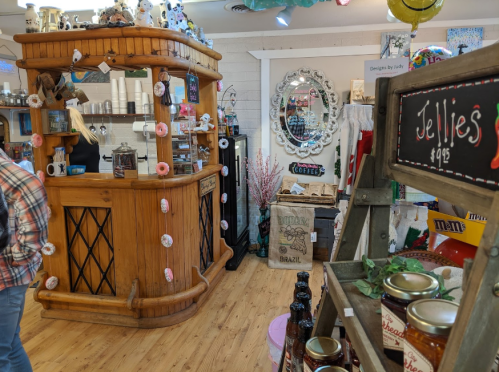 A cozy shop interior featuring a wooden counter, colorful decor, and shelves with jars and snacks.