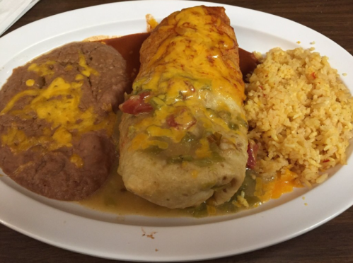 A plate featuring a large burrito topped with cheese, accompanied by refried beans and yellow rice.