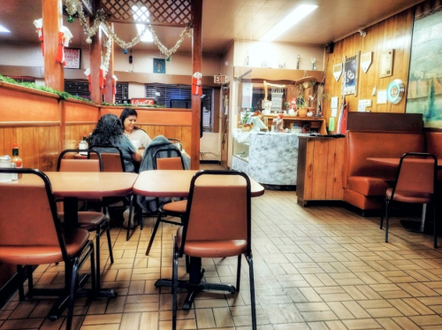 Two people sit at a table in a cozy restaurant with wooden decor and festive decorations in the background.