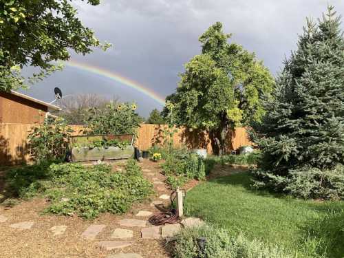 A vibrant garden with a stone path, sunflowers, and a rainbow arching over a cloudy sky in the background.