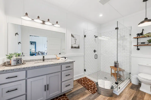 Modern bathroom featuring a glass shower, double sink vanity, and stylish decor with a warm color palette.