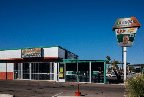 Exterior of "El Guero Canelo" restaurant with a sign and clear blue sky, showcasing a vibrant, inviting atmosphere.