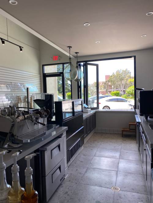 A modern coffee shop interior with an open window, showcasing equipment and a bright, inviting atmosphere.