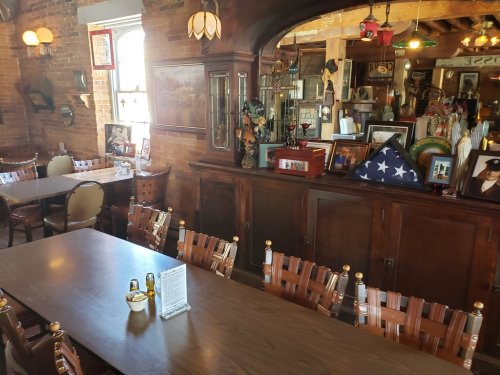 A cozy dining area with wooden furniture, vintage decor, and a display of memorabilia on the walls.
