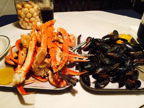 A seafood feast featuring a platter of crab legs and a platter of mussels, served with dipping sauces.